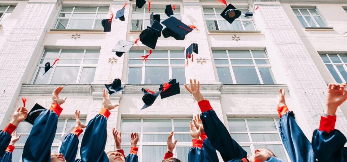 Kenyan university students throwing caps up after graduating
